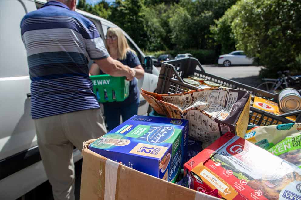 Two people carrying crates of food for donations.